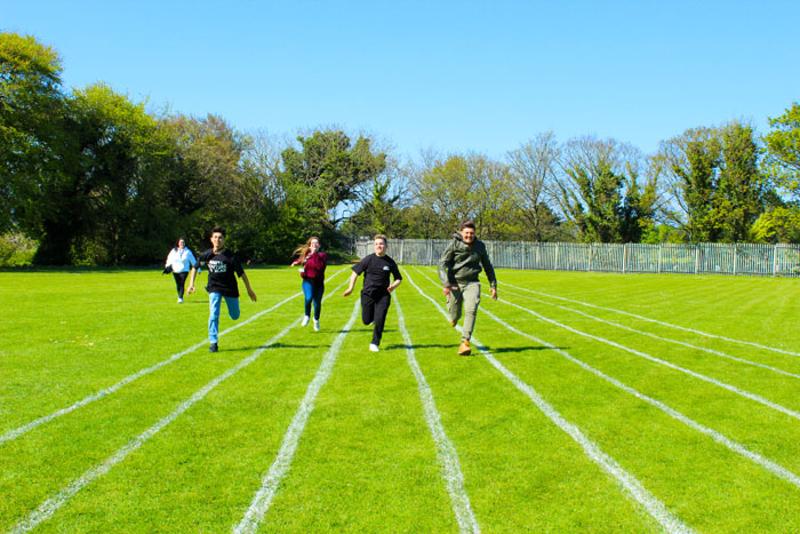Kinder laufen auf einer Irland Sprachreise auf einer grünen Wiese um die Wette