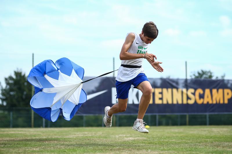 Im Tennis-Camp-Kinder sprintet der Teilnehmer mit einem Schirm auf dem Rücken