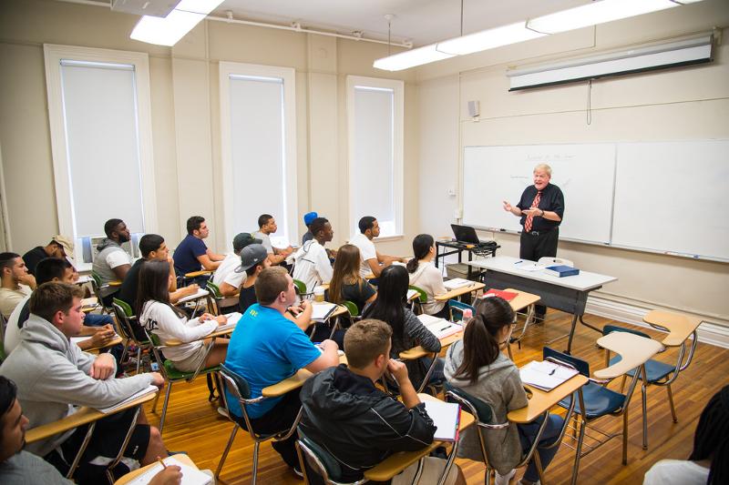 Die Teilnehmer einer Sprachreise New York werden im Klassenraum von einer Lehrerin unterrichtet