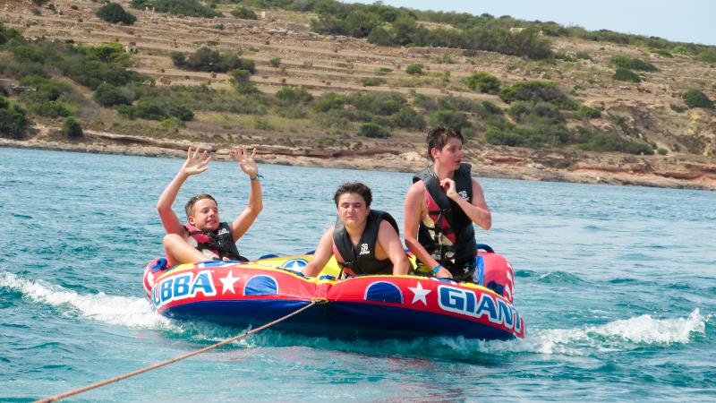 Jugendliche lassen sich in den Sprachferien Malta auf einem Schlauchboot über das Wasser ziehen
