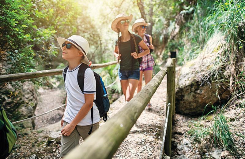 Drei Kinder wandern durch eine Schlucht im Sommercamp Linz