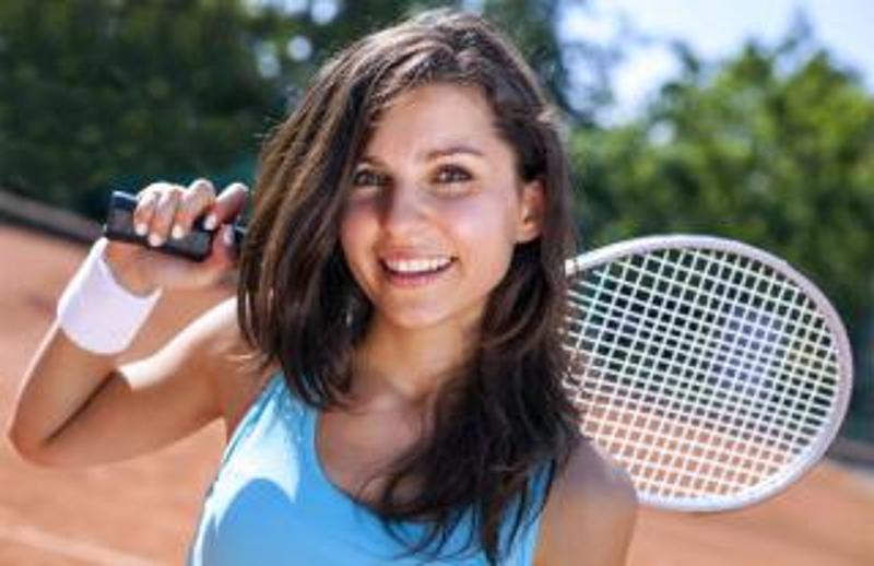Teilnehmerin eines Tennisferiencamps hält einen Schläger über der Schulter