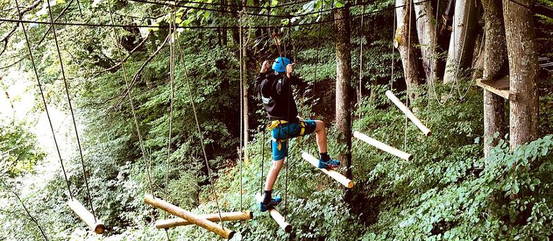 Ein Kind balanciert auf Hölzern durch den Kletterpark im Feriencamp Mondsee