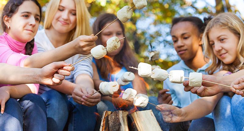 Auf einer Juvigo Sprachreise sitzen die Kinder an einem Lagerfeuer mit Marshmallows